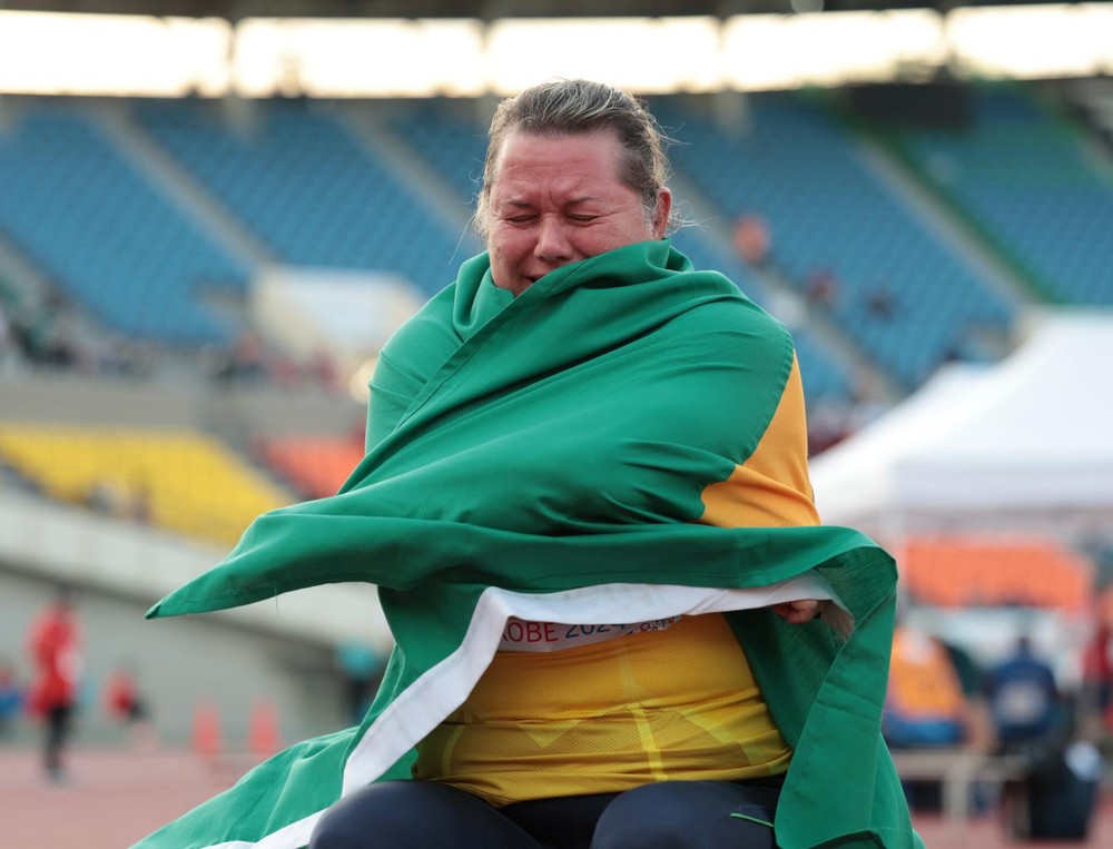 Beth Gomes emocionada abraçando a bandeira do Brasil